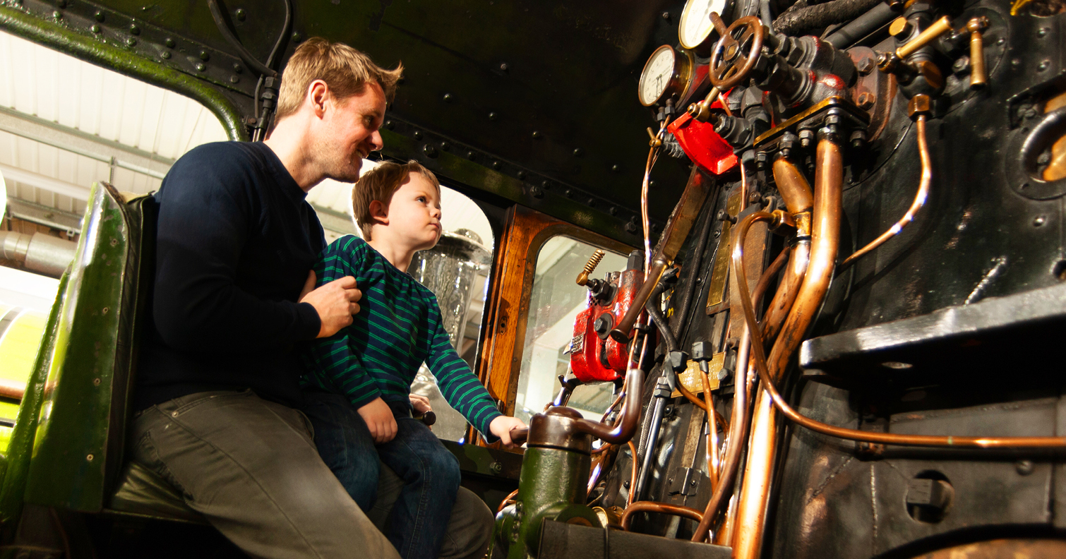 dad and son sat inside a railway engine cab at Locomotion, Shildon